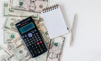 Flat lay of US dollar bills with calculator and notebook for budgeting.