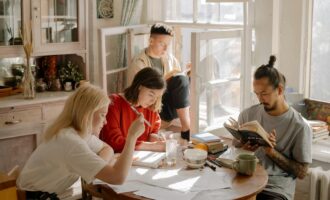 A group of college students studying in a bright, cozy room with natural light.